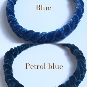 May include: Two velvet headbands, one blue and one petrol blue. The headbands are braided and are shown on a white background.