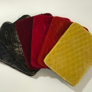 May include: Six quilted laptop sleeves in various colors, including black, red, and gold. The sleeves are made of a soft, velvety material and have a diamond-shaped quilting pattern.