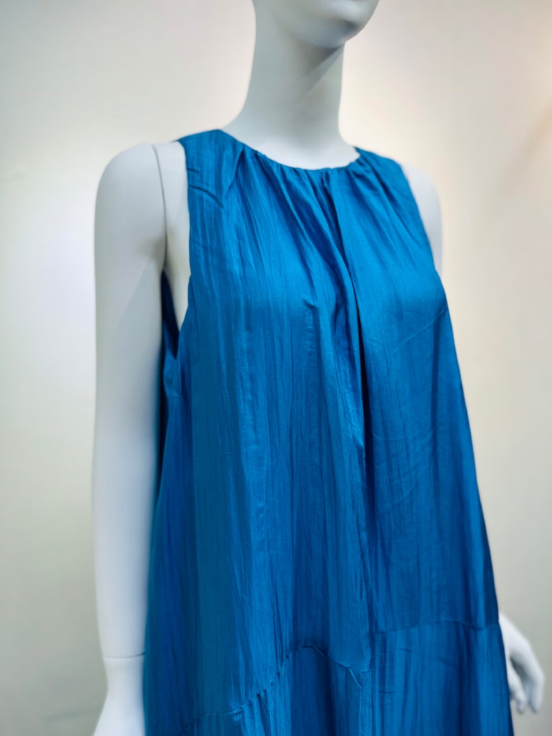 May include: A sleeveless, blue, flowing dress with a gathered neckline.