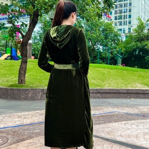 May include: A long, dark green velvet robe with a hood and a belt. The robe is cinched at the waist and has a flowing skirt.