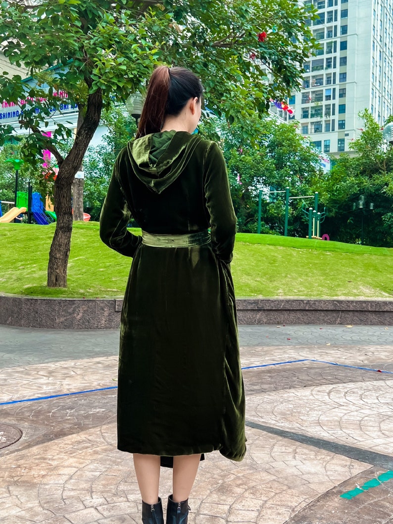 May include: A long, dark green velvet robe with a hood and a belt. The robe is cinched at the waist and has a flowing skirt.