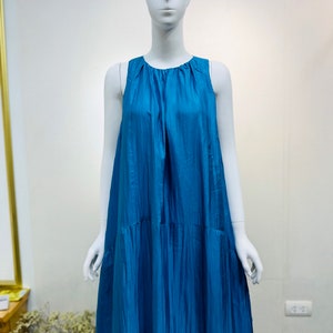 May include: A sleeveless maxi dress in a vibrant teal blue color. The dress has a gathered neckline and a flowing, A-line silhouette.