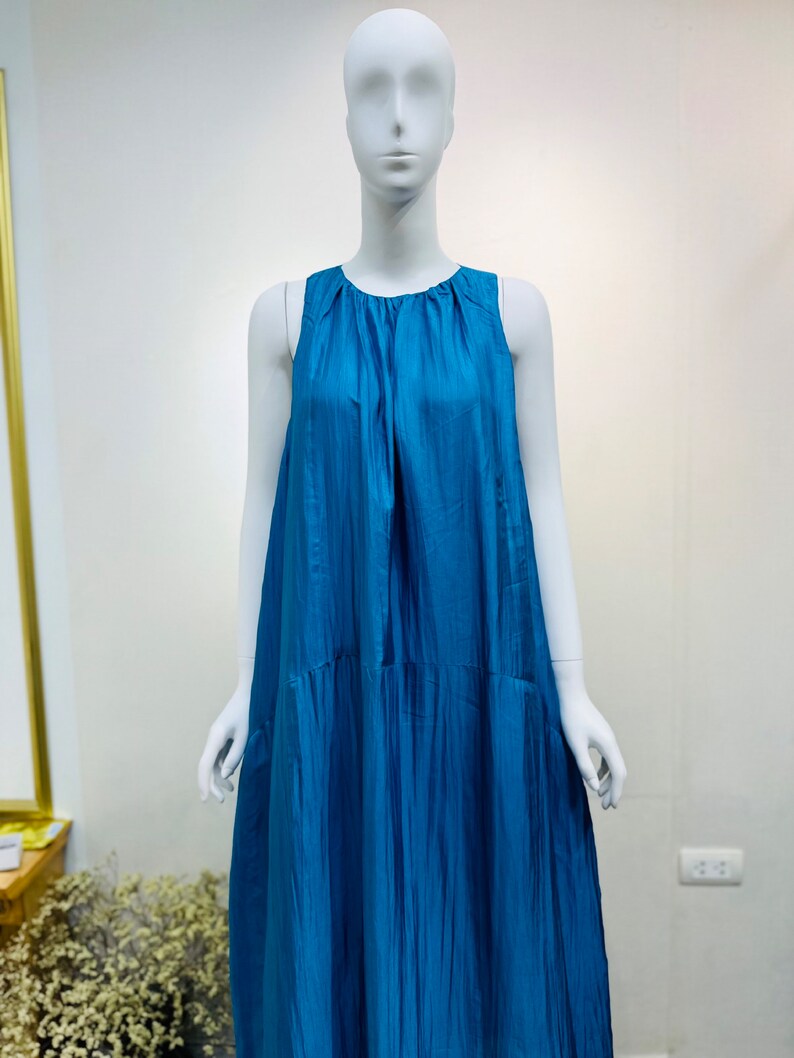 May include: A sleeveless maxi dress in a vibrant teal blue color. The dress has a gathered neckline and a flowing, A-line silhouette.