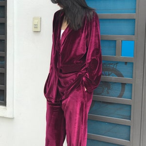 May include: A burgundy velvet pantsuit with a long-sleeved blazer and wide-leg pants.