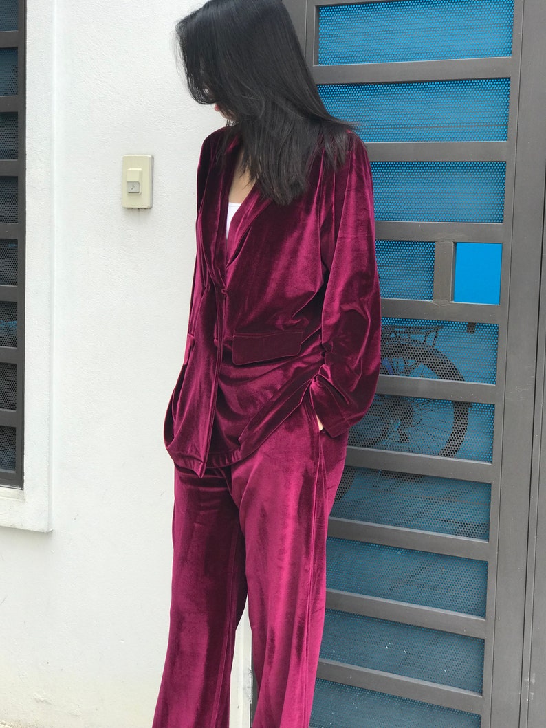 May include: A burgundy velvet pantsuit with a long-sleeved blazer and wide-leg pants.