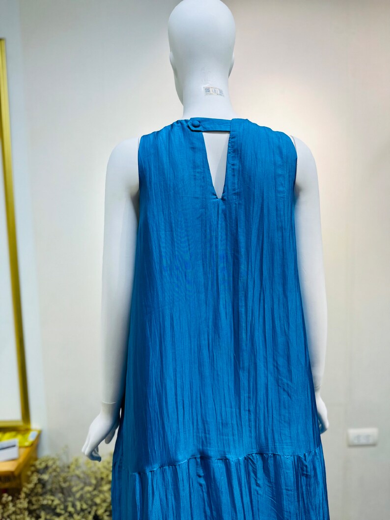 May include: A sleeveless maxi dress in a vibrant blue color. The dress has a V-neckline and a keyhole opening in the back. The fabric has a slightly textured, crinkled look.