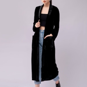 Peut inclure: Une femme portant un long manteau en velours noir avec un col en satin, un jean bleu et des bottines noires.