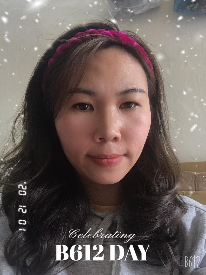 May include: A woman with long dark hair is wearing a pink velvet headband. She is smiling and looking at the camera. The text "Celebrating B612 DAY" is written on the image.