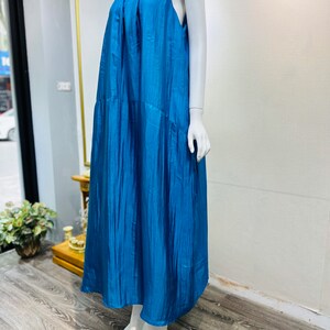 May include: A sleeveless maxi dress in a vibrant teal blue color. The dress has a flowing, relaxed fit and a simple, elegant design.