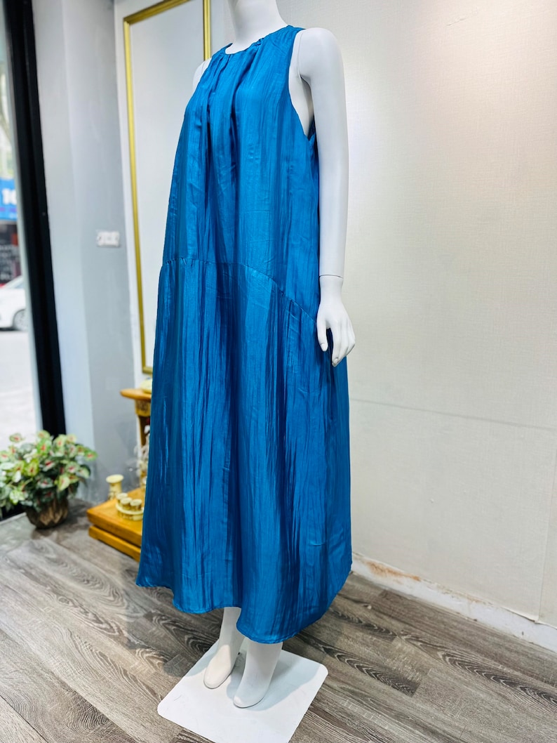 May include: A sleeveless maxi dress in a vibrant teal blue color. The dress has a flowing, relaxed fit and a simple, elegant design.