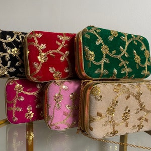 May include: Five different velvet clutches with gold embroidery and sequins. The clutches are in shades of black, red, green, pink, and beige.