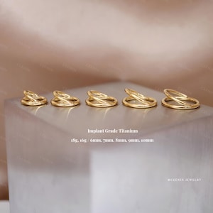 May include: Five gold-colored, double-banded rings of varying sizes are displayed on a light-colored surface. The rings are made of implant-grade titanium and are available in sizes ranging from 6mm to 10mm. The text "Implant Grade Titanium" is visible.
