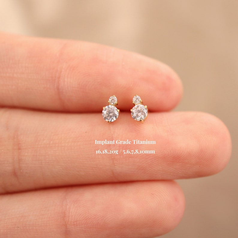Puede incluir: Un par de peque&ntilde;os pendientes de titanio dorado con dos piedras redondas de circonita c&uacute;bica transparentes. Los pendientes tienen un di&aacute;metro de 5,6 a 7,8 mm y pesan 16,18 gramos.