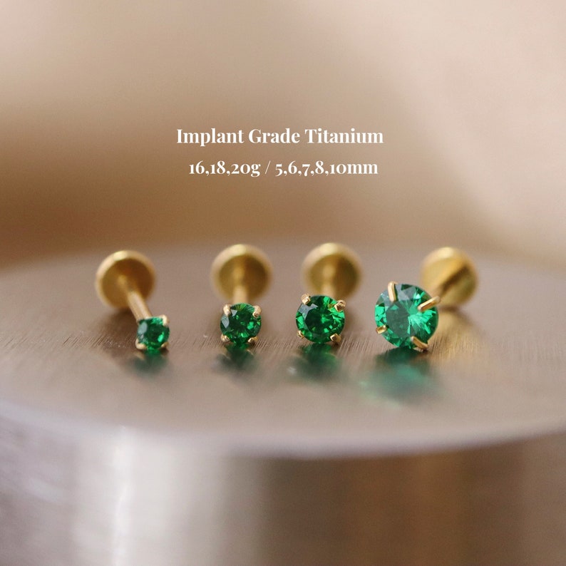 May include: Four gold titanium body jewelry studs with green gemstones. The studs are 16, 18, 20 gauge and 5, 6, 7, 8, 10 mm in size. Implant Grade Titanium.