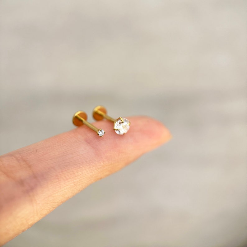 Puede incluir: Dos piezas de joyer&iacute;a corporal de oro con piedras preciosas transparentes. La pieza m&aacute;s grande tiene una piedra preciosa m&aacute;s grande y la pieza m&aacute;s peque&ntilde;a tiene una piedra preciosa m&aacute;s peque&ntilde;a.