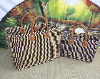 May include: Two striped woven tote bags with brown leather handles. The larger bag is black and cream striped, and the smaller bag is navy and cream striped.