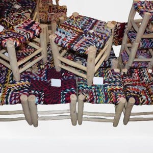 Peut inclure: Ensemble de petits tabourets en bois avec des assises tissées. Les sièges présentent un motif coloré avec des nuances de rouge, de bleu, de vert et de jaune. Les tabourets ont un aspect rustique et fait à la main.