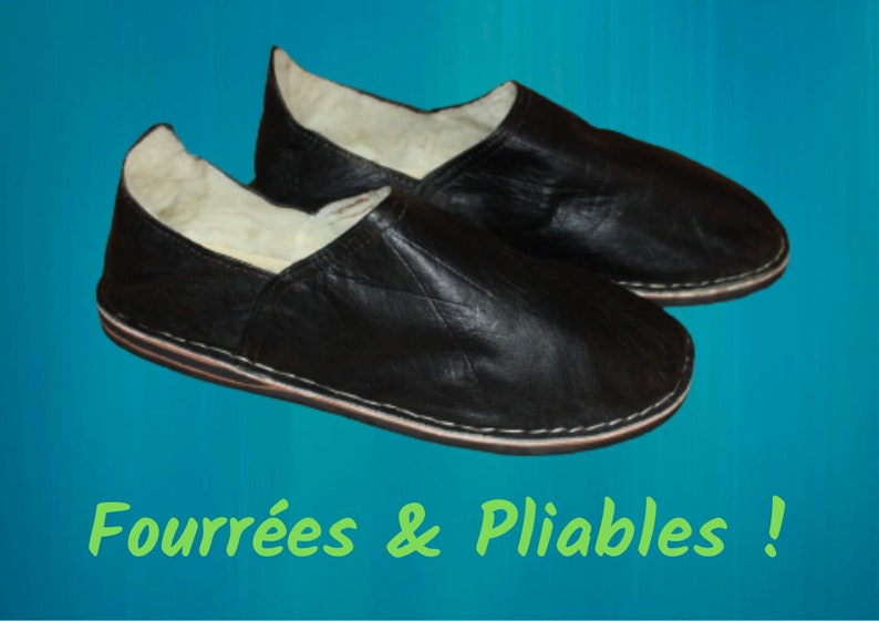 Op de afbeelding: Een paar zwarte leren slippers met een witte bontvoering. De slippers zijn gevouwen en hebben een gestikte naad rond de rand. De tekst "Fourr&eacute;es & Pliables!" staat in het groen onder de slippers.