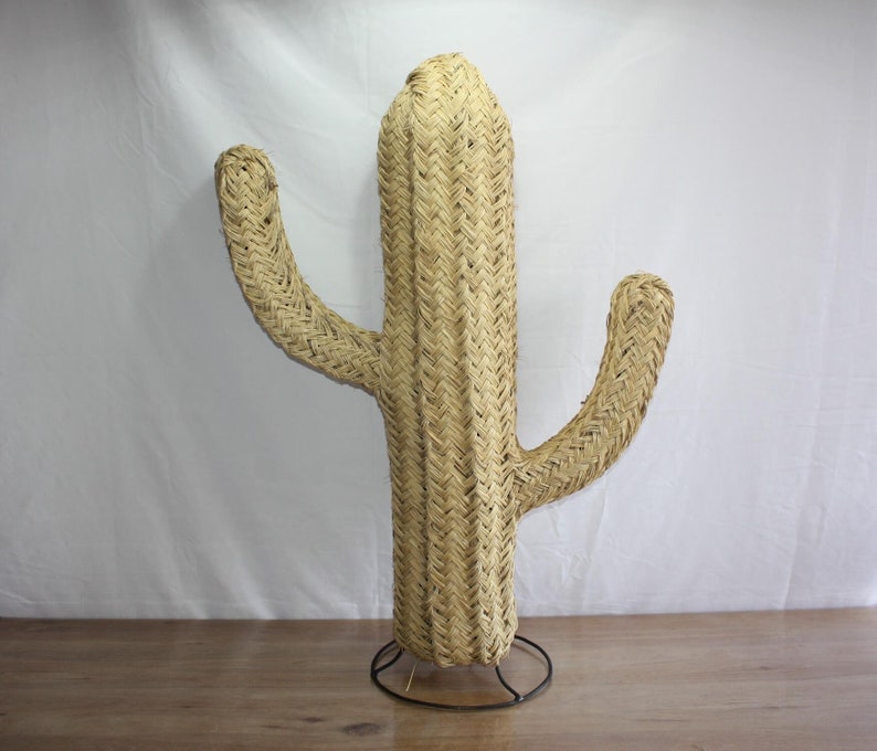 Puede incluir: Una gran escultura de cactus de paja tejida con una base marr&oacute;n. El cactus est&aacute; hecho de materiales naturales y tiene un estilo r&uacute;stico del suroeste.