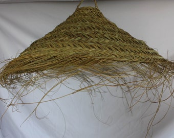 Peut inclure: Un grand abat-jour en fibres naturelles tissées, de forme conique et avec un bord frangé. L'abat-jour est fait d'un matériau brun clair et a un aspect rustique et naturel.