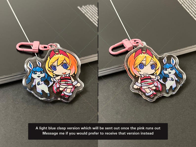 May include: A clear acrylic charm featuring a cartoon character with orange hair and a blue creature, attached to a pink plastic lobster clasp. The text reads: A light blue clasp version which will be sent out once the pink runs out. Message me if you would prefer to receive that version instead.