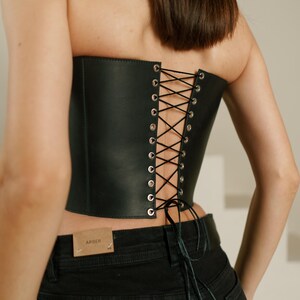 A woman wearing a black corset with a lace-up back detail.