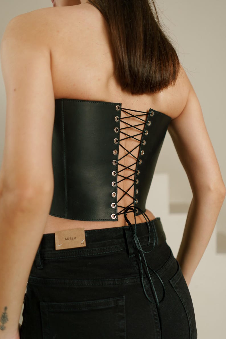 A woman wearing a black corset with a lace-up back detail.