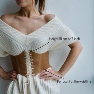a woman wearing a white dress with a brown belt