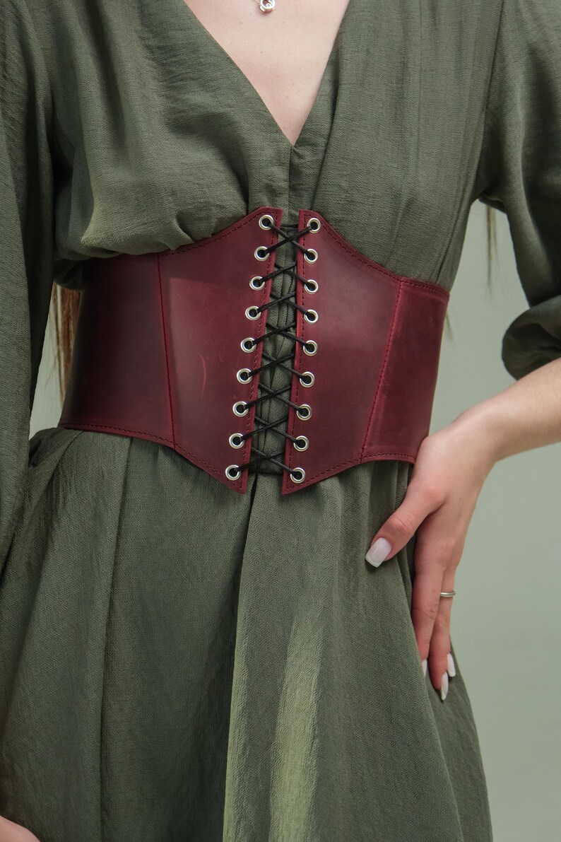 A close-up of a person wearing a green dress with a red corset belt.