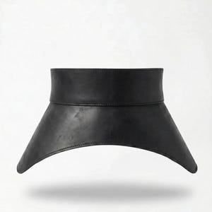 May include: A wide black belt featuring a structured, high-waisted design with a smooth finish. The belt has a straight top edge and a curved, flared bottom hem that extends outward, creating a distinct silhouette with visible stitching.