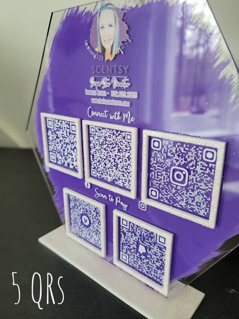 Pode incluir: Uma placa hexagonal de acr&iacute;lico roxo com cinco c&oacute;digos QR emoldurados em branco. A placa tem o texto "SCENTSY Super Star Director" e "Connect with Me" impresso nela.