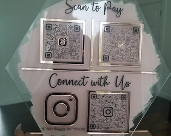 Puede incluir: Un letrero de vidrio con fondo blanco y texto negro que dice "Scan to Pay" y "Connect with Us". Hay cuatro códigos QR en el letrero, dos para el pago y dos para las redes sociales. El letrero también incluye el logotipo de Instagram y el texto "@EVENTIENDDETS&T3DECOR".