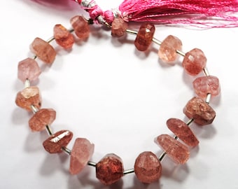 May include: A strand of pink and red gemstone beads with silver spacers. The beads are faceted and have a rough, natural texture. The strand is strung on a silver wire and has a pink tassel at the end.