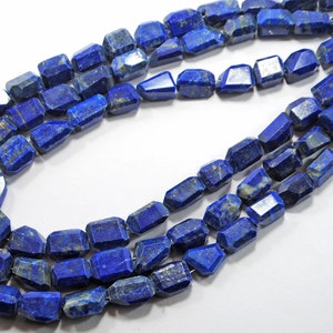 May include: A strand of faceted lapis lazuli beads, each bead is a deep blue with white and gold flecks. The beads are strung on a clear thread.