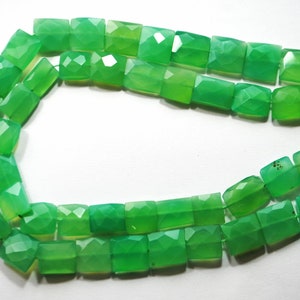 May include: A strand of green gemstone beads, each bead is faceted and has a rectangular shape.
