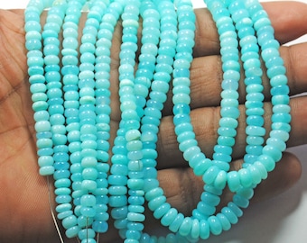 May include: A strand of turquoise blue opal beads, each bead is round and slightly elongated. The beads are strung on a thin wire and are arranged in a loose, flowing pattern.