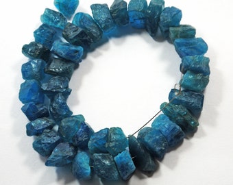 Puede incluir: Una hebra de cuentas de piedra preciosa de apatita azul, cada cuenta tiene una forma irregular y rugosa. Las cuentas están enhebradas en un alambre de plata.