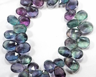May include: A strand of faceted fluorite gemstone beads in shades of green, purple, and blue. The beads are teardrop shaped and have a glossy finish.