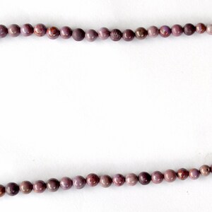 K&ouml;nnte beinhalten: Eine Halskette aus violetten Edelsteinen mit einem silbernen Verschluss. Die Halskette besteht aus runden Perlen und ist etwa 45 cm lang.