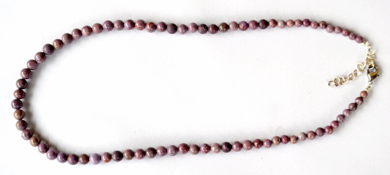 K&ouml;nnte beinhalten: Eine Halskette aus violetten Edelsteinen mit einem silbernen Verschluss. Die Halskette besteht aus runden Perlen und ist etwa 45 cm lang.