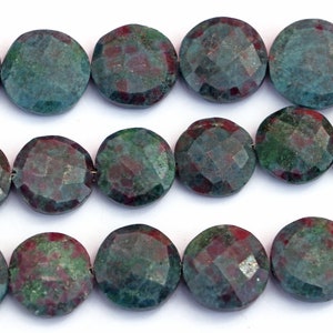 May include: A strand of green and red gemstone beads. The beads are round and have a faceted finish.