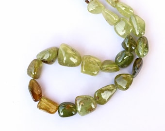 Puede incluir: Una hebra de cuentas de piedras preciosas verdes y marrones, cada cuenta tiene una forma irregular y lisa.