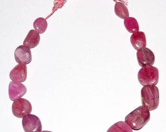 May include: A strand of pink gemstone beads with a pink tassel at each end. The beads are smooth and oval-shaped.