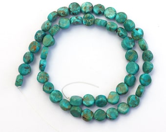 May include: Strand of turquoise gemstone beads. The beads are a vibrant turquoise color with brown matrix patterns. The beads are round and flat, strung on a white string. The beads are approximately 0.5 inches in diameter.