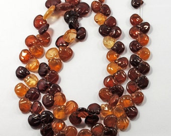 May include: A strand of brown, orange, and red gemstone beads. The beads are faceted and have a leaf-like design.