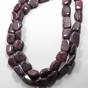 Könnte beinhalten: Eine Kette aus violetten Edelsteinperlen, jede Perle hat eine glatte, flache, ovale Form.