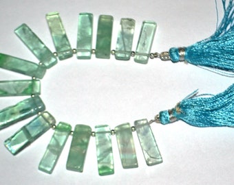 May include: A strand of light green fluorite gemstone beads with a light blue tassel on each end.