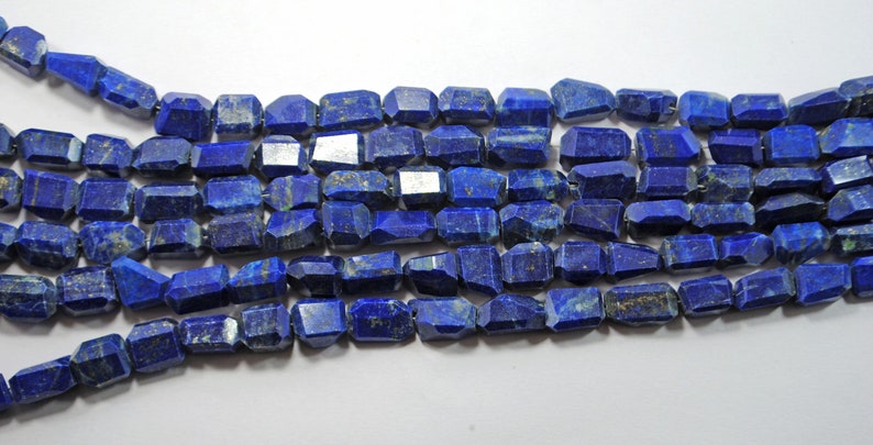 May include: A strand of dark blue lapis lazuli beads, each bead is faceted and has a rectangular shape.