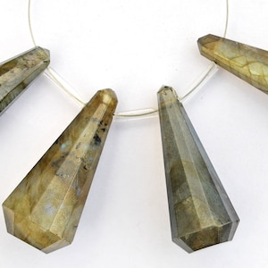 Peut inclure: Quatre perles de labradorite facettées en forme de larme, enfilées sur un cordon transparent. Les perles sont un mélange de vert, de gris et d'or.