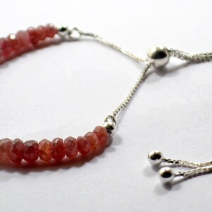 Op de afbeelding: Een armband van roze edelstenen met een verstelbare sluiting van zilver. De armband is gemaakt van kleine, gefacetteerde edelstenen en heeft een delicate, vrouwelijke uitstraling.